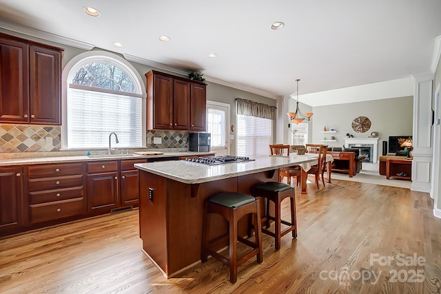 kitchen featuring a kitchen bar, decorative backsplash, a center island, and stainless steel gas cooktop