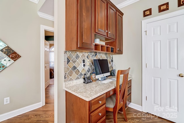 office space with built in desk, dark hardwood / wood-style flooring, and ornamental molding