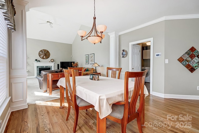 dining space featuring light hardwood / wood-style floors, lofted ceiling, crown molding, ceiling fan with notable chandelier, and washer / clothes dryer