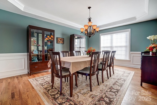 dining room with crown molding, a chandelier, light hardwood / wood-style floors, and a tray ceiling