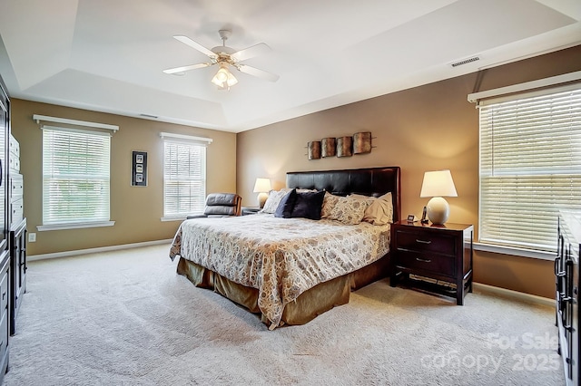 carpeted bedroom with ceiling fan and a tray ceiling