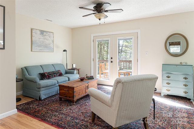 living room featuring a textured ceiling, ceiling fan, hardwood / wood-style floors, and french doors