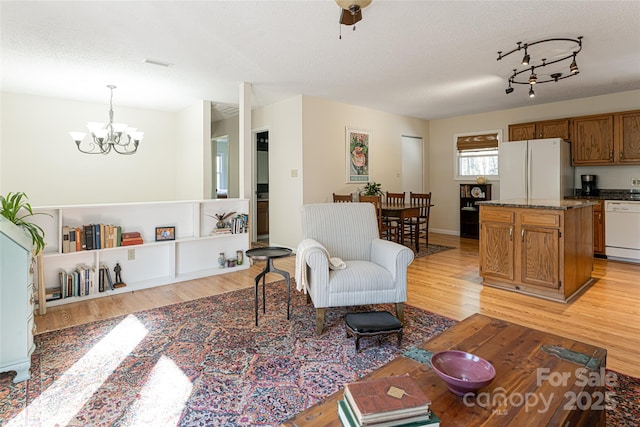 living room with a textured ceiling, light hardwood / wood-style flooring, and a notable chandelier