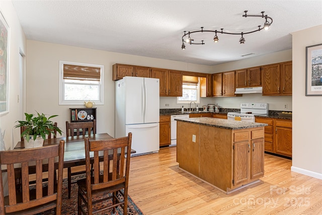 kitchen with white appliances, a textured ceiling, a center island, sink, and light hardwood / wood-style flooring