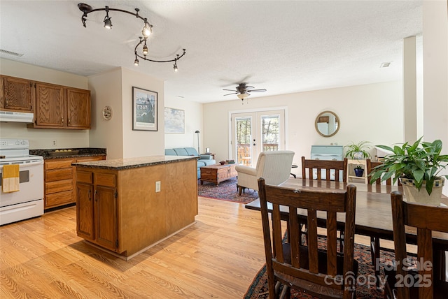 kitchen with a textured ceiling, a center island, electric stove, light wood-type flooring, and ceiling fan