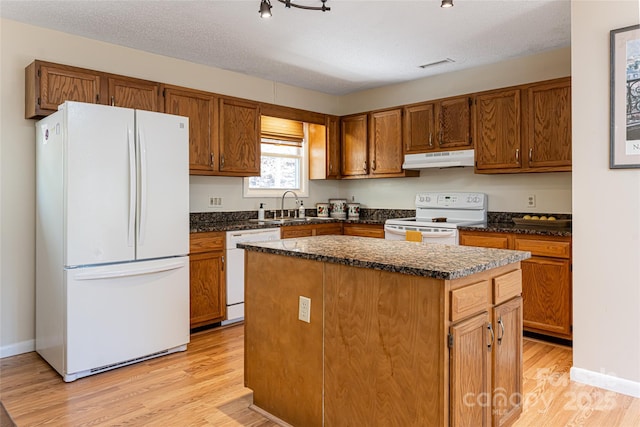 kitchen with a textured ceiling, sink, a center island, and white appliances