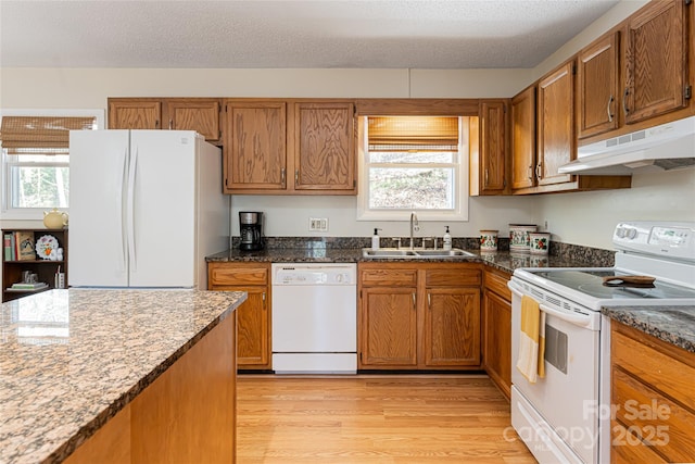 kitchen with a textured ceiling, sink, light wood-type flooring, and white appliances