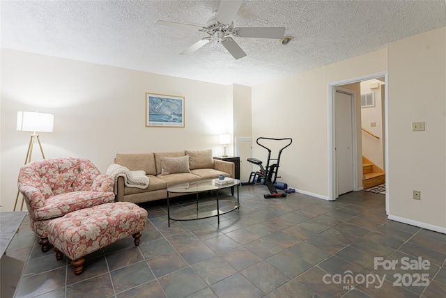 living room with ceiling fan and a textured ceiling