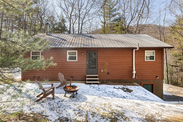 snow covered back of property with an outdoor fire pit