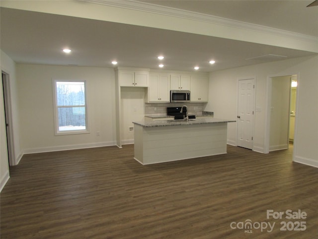 kitchen featuring light stone counters, dark hardwood / wood-style flooring, an island with sink, decorative backsplash, and white cabinets