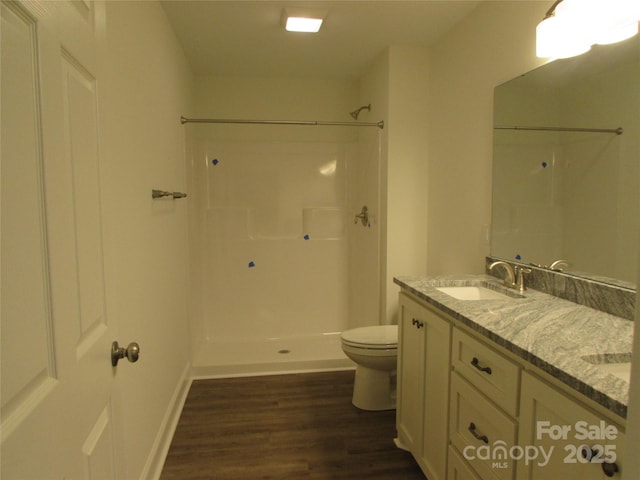 bathroom featuring a shower, wood-type flooring, vanity, and toilet