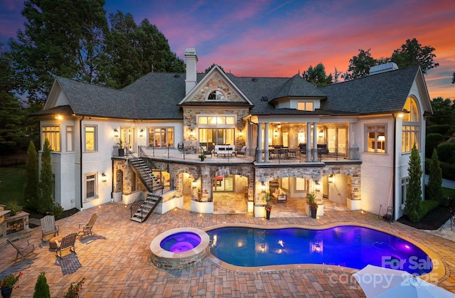 back house at dusk with a patio area and a swimming pool with hot tub