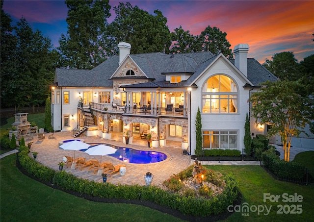 back house at dusk with a fireplace and a patio