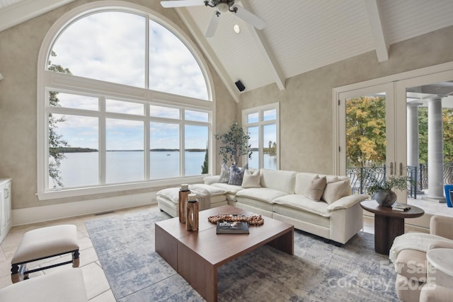 tiled living room with high vaulted ceiling, a water view, ornate columns, a wealth of natural light, and beamed ceiling