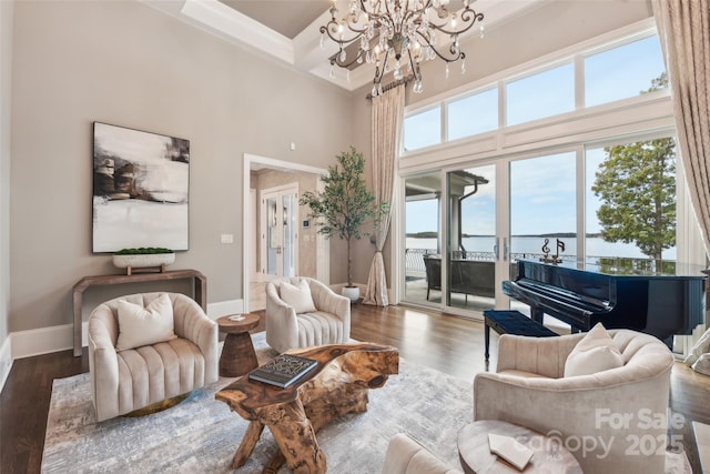 living room with a high ceiling, coffered ceiling, dark hardwood / wood-style flooring, a chandelier, and a water view