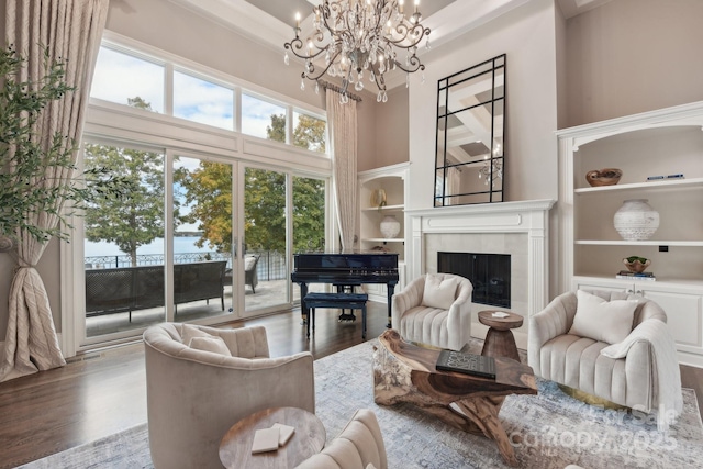 living room with a tile fireplace, wood-type flooring, a towering ceiling, and a chandelier