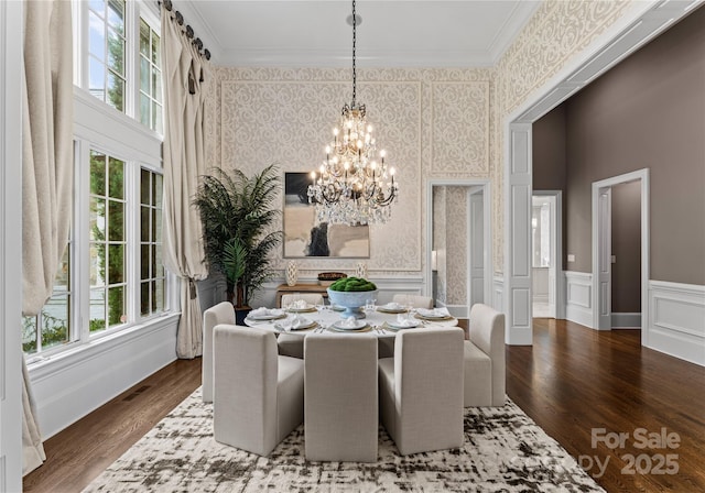 dining space featuring hardwood / wood-style floors, a notable chandelier, ornamental molding, and a wealth of natural light