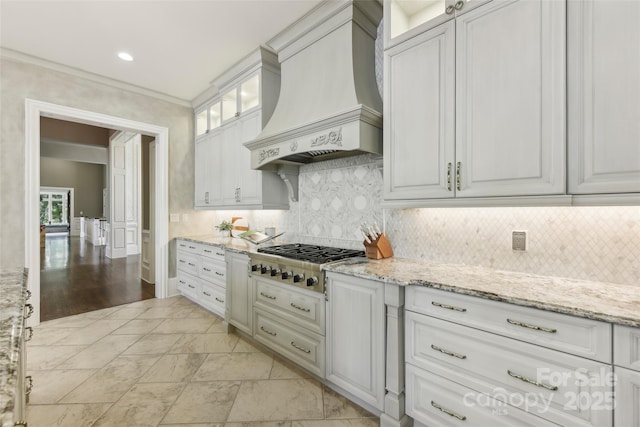 kitchen featuring premium range hood, decorative backsplash, light stone countertops, white cabinetry, and stainless steel gas cooktop