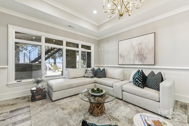 living room with hardwood / wood-style floors, an inviting chandelier, crown molding, and a tray ceiling