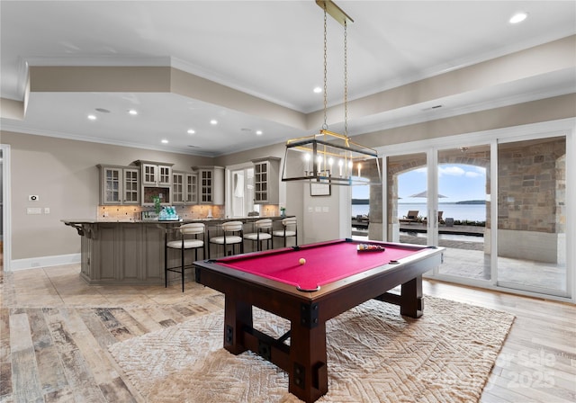 rec room featuring light hardwood / wood-style flooring, billiards, crown molding, bar, and a water view