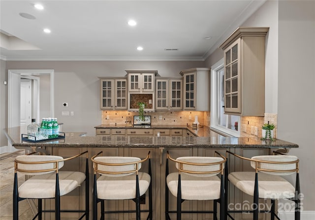 kitchen featuring kitchen peninsula, decorative backsplash, a breakfast bar, and dark stone counters