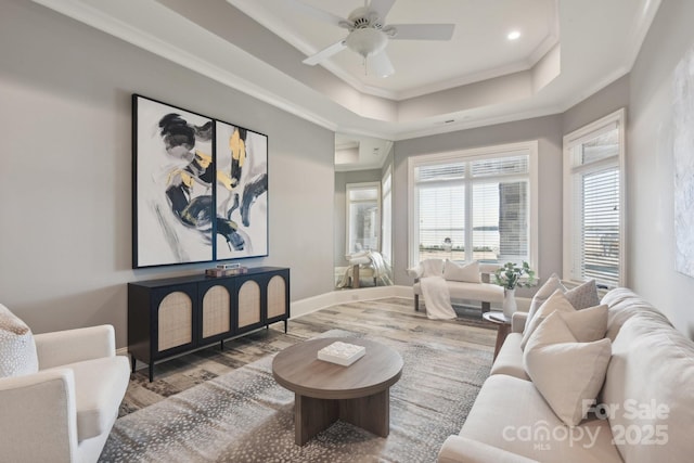 living room featuring light hardwood / wood-style floors, ceiling fan, crown molding, and a tray ceiling