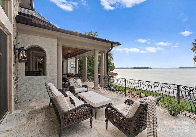 view of patio with a water view, ceiling fan, and a balcony