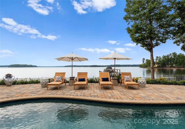 view of swimming pool with a water view and a patio area