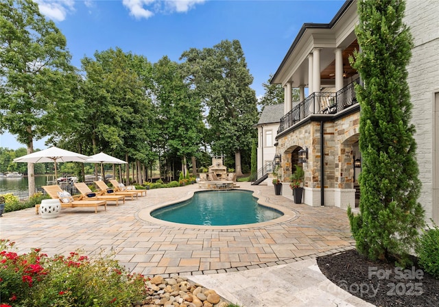 view of pool featuring an outdoor fireplace and a patio