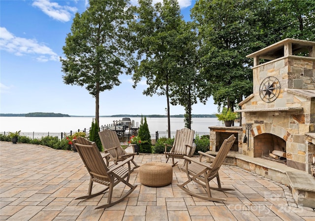 view of patio / terrace featuring an outdoor stone fireplace and a water view