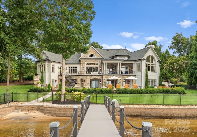 rear view of property with a balcony, a yard, and a water view