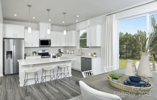 kitchen featuring white cabinets, decorative light fixtures, and stainless steel appliances