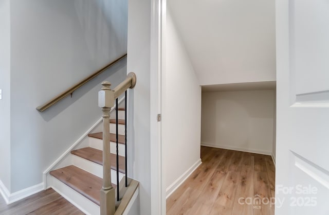 stairway with wood-type flooring and lofted ceiling