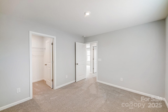 unfurnished bedroom featuring light colored carpet, a spacious closet, and a closet