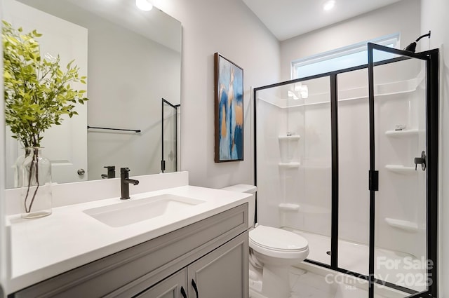 bathroom featuring a shower with door, vanity, and toilet