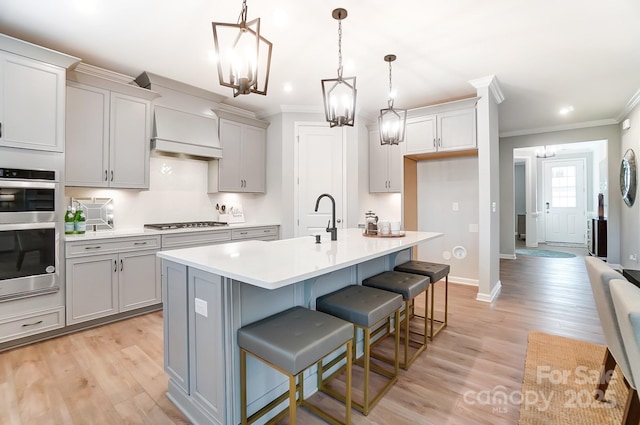 kitchen with stainless steel appliances, a kitchen bar, decorative light fixtures, and a kitchen island with sink