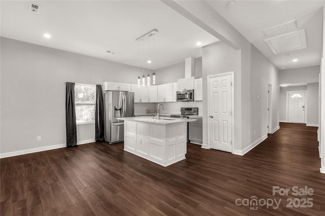 kitchen with a center island with sink, appliances with stainless steel finishes, hanging light fixtures, dark hardwood / wood-style floors, and sink