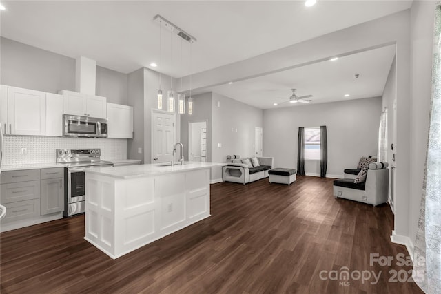 kitchen featuring hanging light fixtures, an island with sink, white cabinetry, appliances with stainless steel finishes, and ceiling fan