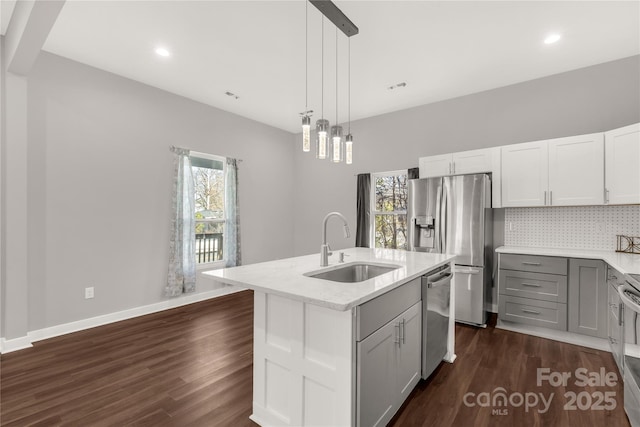 kitchen with sink, an island with sink, backsplash, hanging light fixtures, and appliances with stainless steel finishes