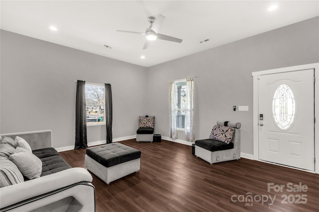 living room with dark wood-type flooring, ceiling fan, and plenty of natural light