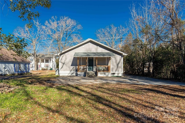 rear view of property with covered porch and a lawn