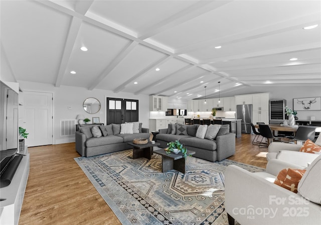 living room with vaulted ceiling with beams and light wood-type flooring