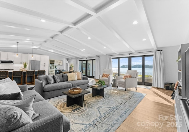 living room with a water view, lofted ceiling with beams, and light wood-type flooring