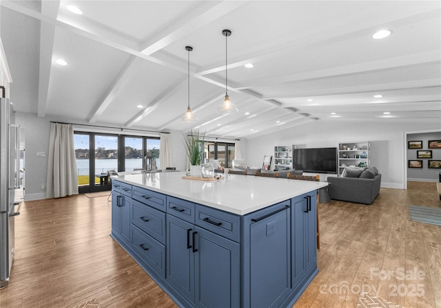 kitchen featuring decorative light fixtures, a kitchen island, blue cabinets, and light hardwood / wood-style flooring