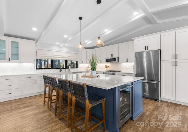 kitchen with vaulted ceiling with beams, white cabinetry, a kitchen island, and stainless steel appliances