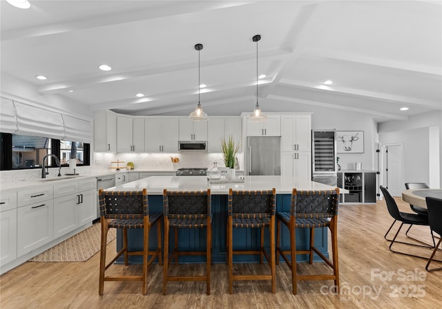 kitchen with vaulted ceiling with beams, light hardwood / wood-style flooring, a kitchen island, and appliances with stainless steel finishes