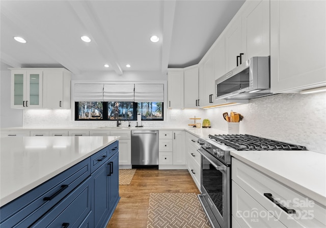 kitchen featuring white cabinetry, stainless steel appliances, beamed ceiling, blue cabinets, and light wood-type flooring