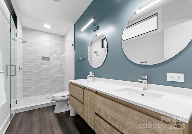 bathroom with wood-type flooring, vanity, toilet, and a shower with shower door