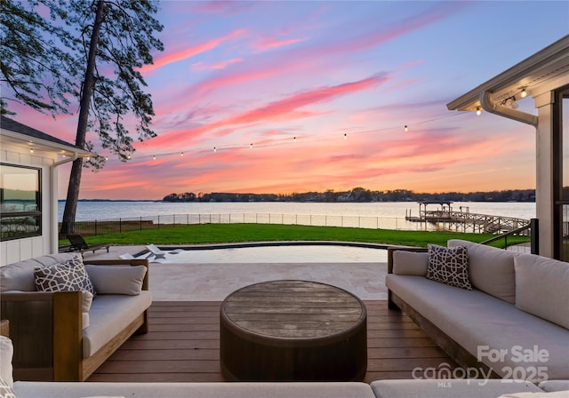 deck at dusk with a lawn, an outdoor living space, and a water view