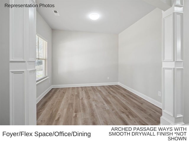 unfurnished room featuring light wood-type flooring and ornate columns